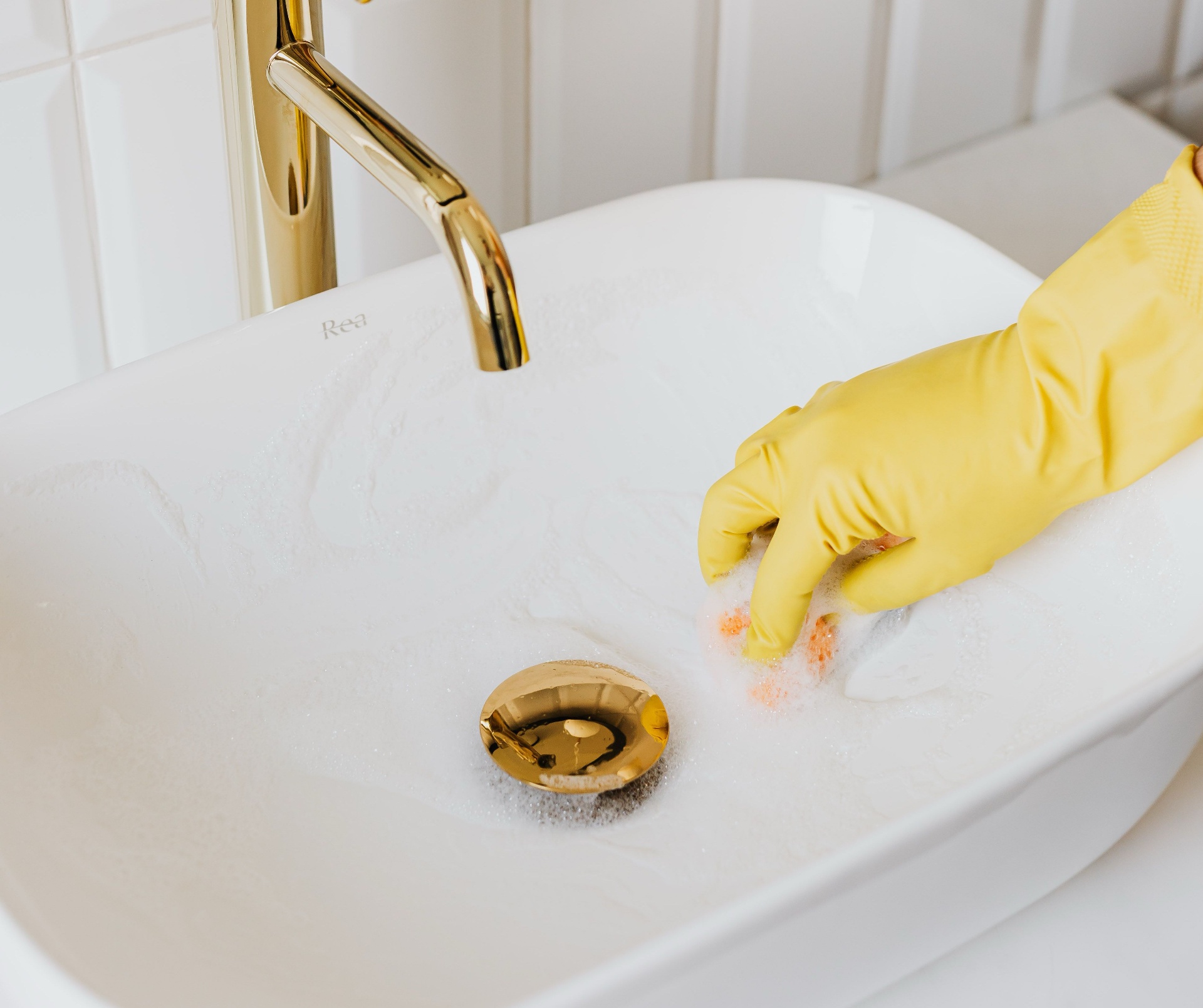Gloved hand cleaning a bright bathroom sink — watch the Kingdom Path cleaning reel