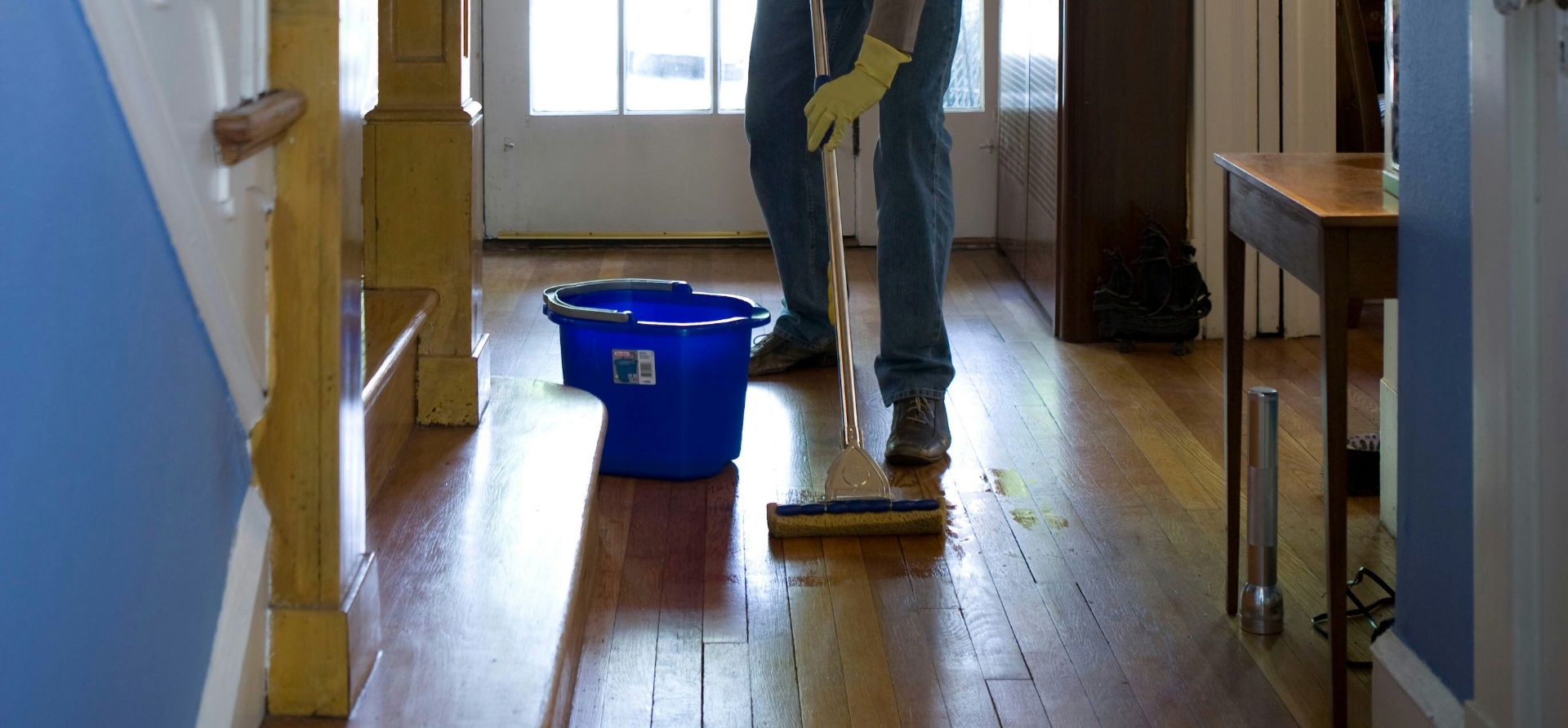 Professional mopping a hardwood floor in a bright home hallway