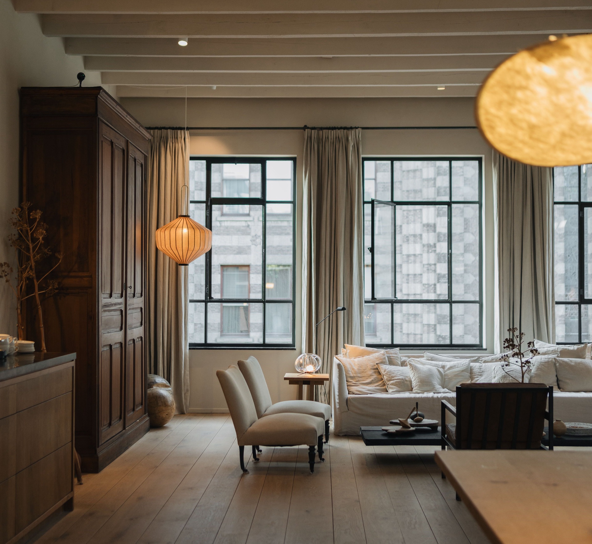 Warm, softly lit living room with linen sofa and wood beams refreshed for a new season in a Michigan home